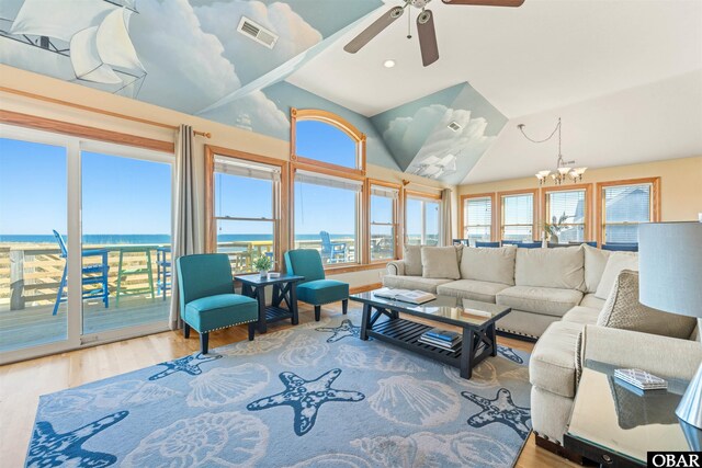 living area with visible vents, vaulted ceiling, wood finished floors, and ceiling fan with notable chandelier