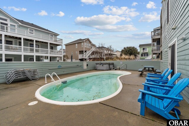 view of swimming pool featuring a residential view, a patio area, and a hot tub