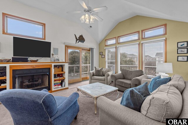 living area with a fireplace, high vaulted ceiling, a ceiling fan, and light colored carpet