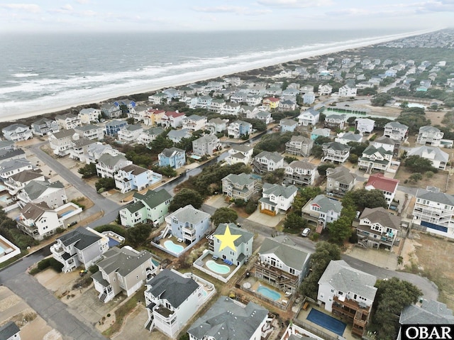 birds eye view of property featuring a water view, a residential view, and a beach view