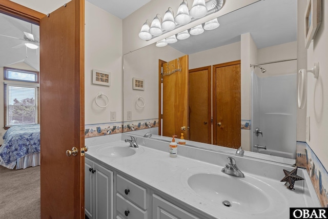 bathroom with double vanity, tub / shower combination, a sink, and ensuite bathroom