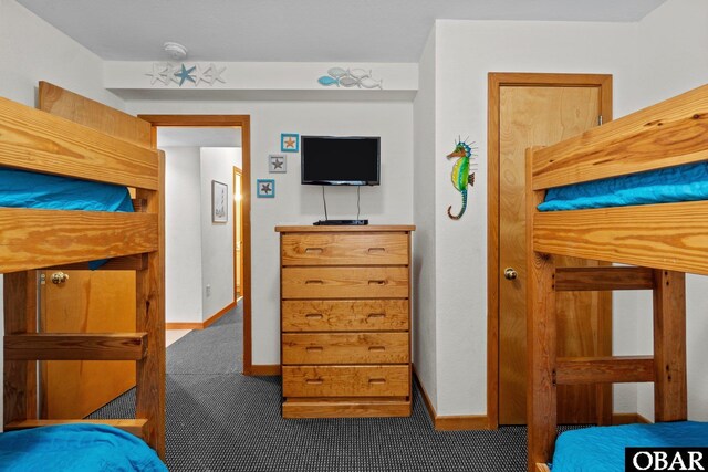 bedroom featuring dark carpet and baseboards