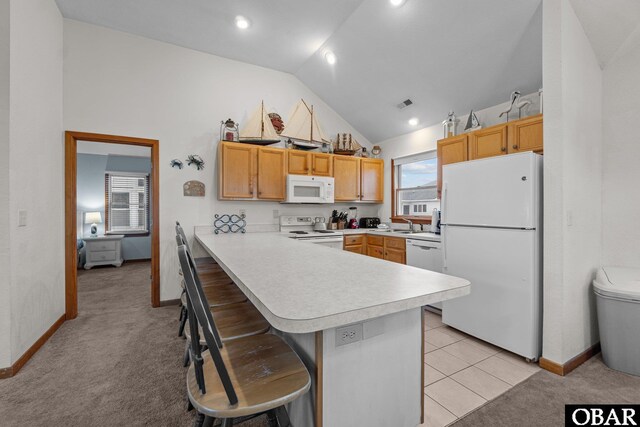 kitchen featuring white appliances, a breakfast bar area, a peninsula, vaulted ceiling, and light countertops