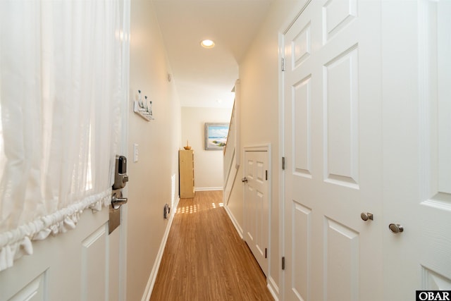 hall featuring light wood finished floors, baseboards, and recessed lighting