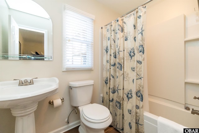 bathroom featuring a sink, shower / bath combination with curtain, toilet, and baseboards