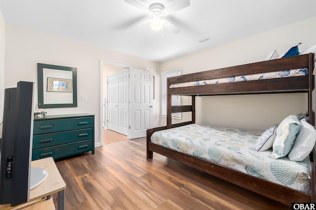 bedroom with dark wood-style floors, ceiling fan, visible vents, and baseboards