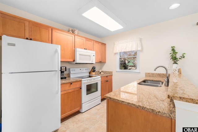 kitchen with white appliances, a sink, a peninsula, and light stone countertops