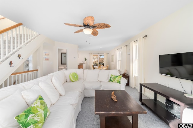 living room with carpet floors, stairway, and a ceiling fan