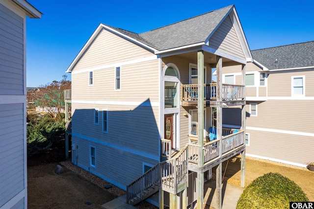 view of property exterior with stairs and roof with shingles