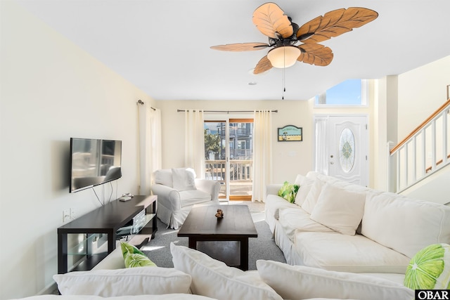 living area with ceiling fan and stairs