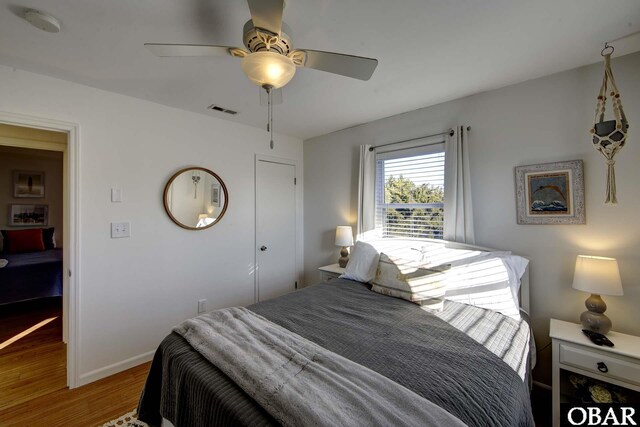 bedroom featuring ceiling fan, wood finished floors, visible vents, and baseboards