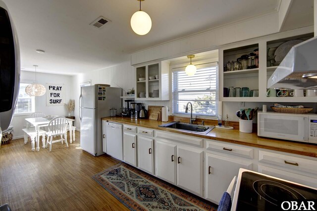 kitchen featuring hanging light fixtures, butcher block counters, and a sink