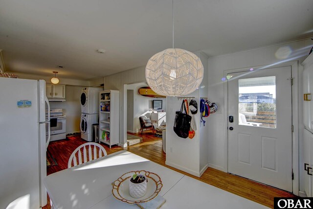 dining space with baseboards, wood finished floors, and stacked washer / drying machine