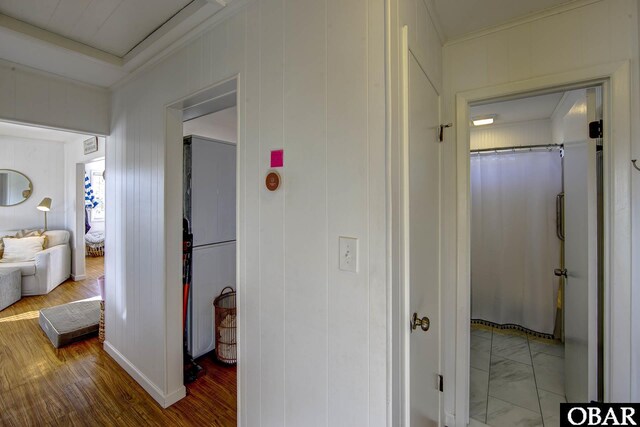 hallway with ornamental molding and wood finished floors