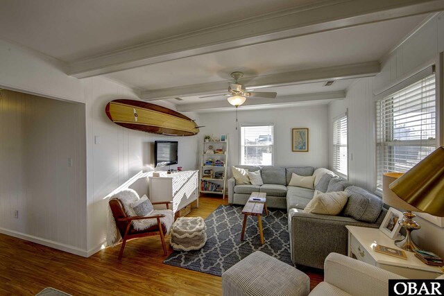living area featuring a ceiling fan, wood finished floors, beam ceiling, and baseboards
