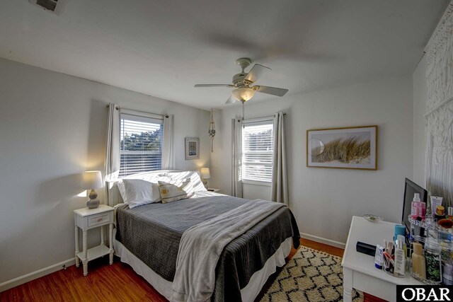 bedroom with multiple windows, wood finished floors, and baseboards