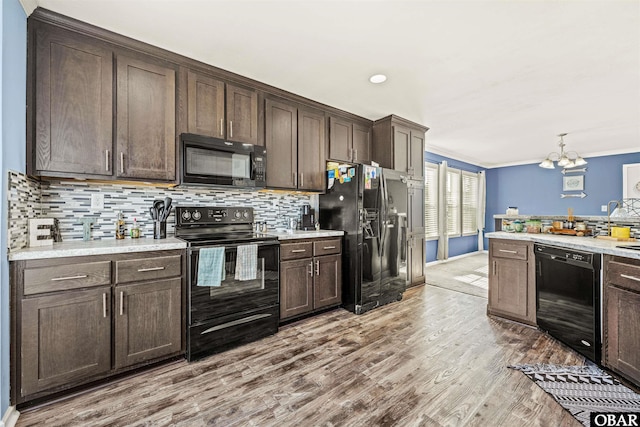 kitchen with tasteful backsplash, light countertops, light wood-style flooring, dark brown cabinetry, and black appliances