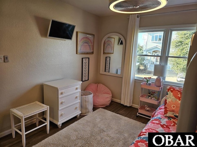 bedroom with a textured wall, dark wood-style flooring, and baseboards