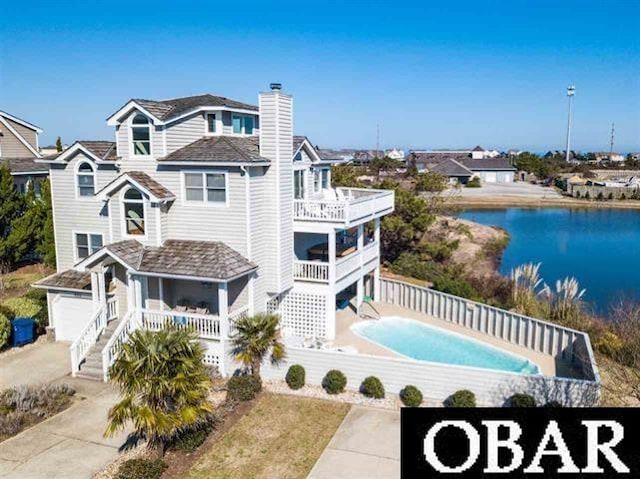 back of property featuring a chimney, a water view, fence, a balcony, and stairs