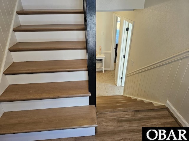 stairs with wood finished floors and wainscoting