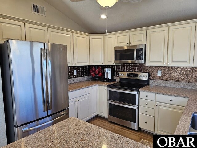 kitchen with lofted ceiling, visible vents, appliances with stainless steel finishes, and backsplash