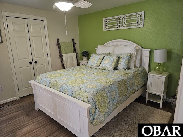 bedroom with dark wood-type flooring, a closet, visible vents, and baseboards