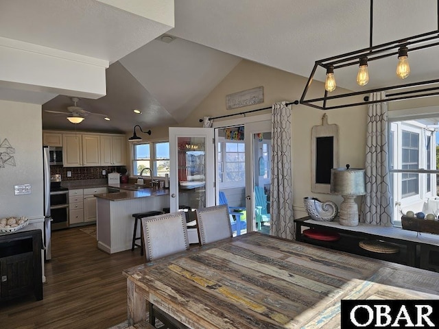 kitchen featuring tasteful backsplash, dark wood finished floors, dark countertops, vaulted ceiling, and a sink