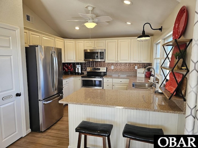 kitchen with a peninsula, a breakfast bar, a sink, visible vents, and appliances with stainless steel finishes