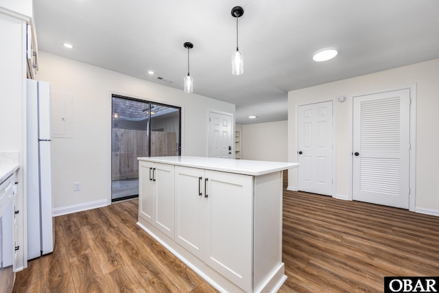 kitchen featuring light countertops, freestanding refrigerator, white cabinetry, and decorative light fixtures