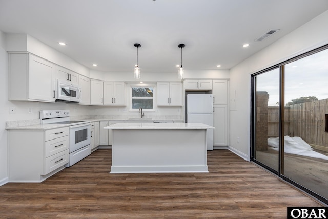 kitchen featuring decorative light fixtures, light countertops, white cabinetry, a sink, and white appliances