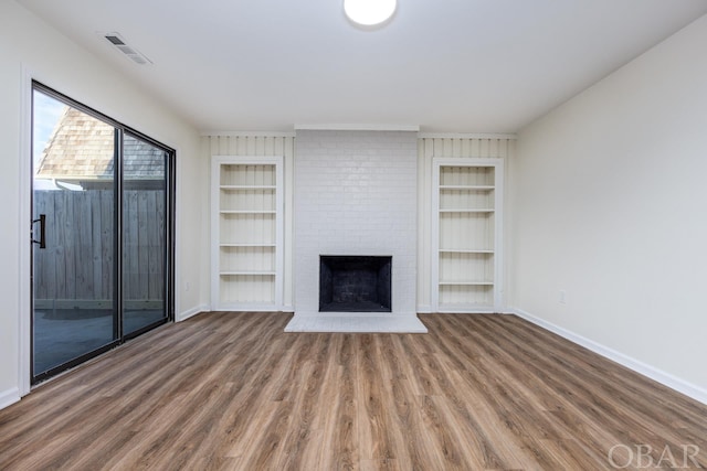 unfurnished living room featuring baseboards, wood finished floors, and built in features