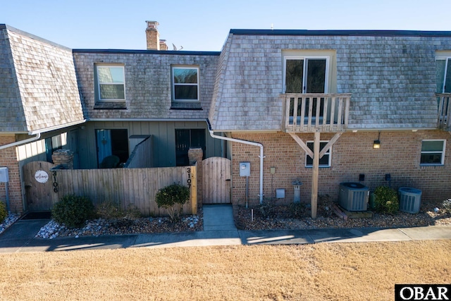 exterior space featuring cooling unit, a gate, roof with shingles, and mansard roof