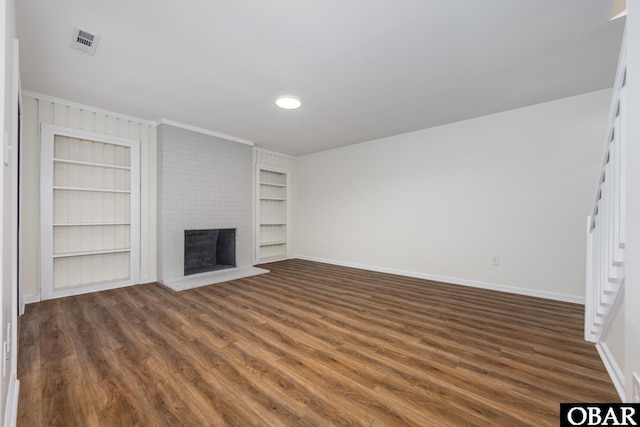 unfurnished living room featuring dark wood-type flooring, a fireplace, built in shelves, and baseboards