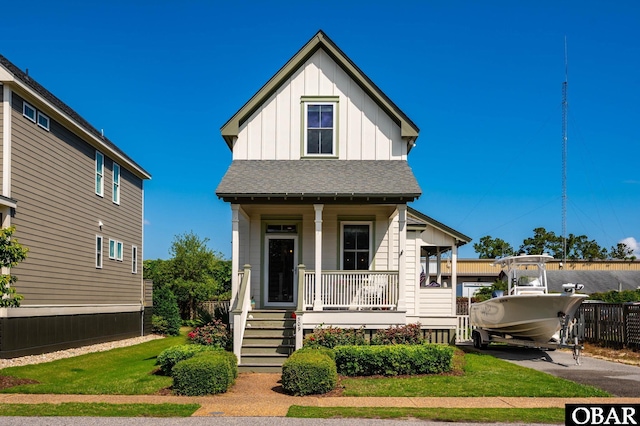 view of front facade featuring board and batten siding, covered porch, and a shingled roof