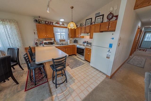 kitchen featuring white appliances, a breakfast bar, hanging light fixtures, light countertops, and a sink