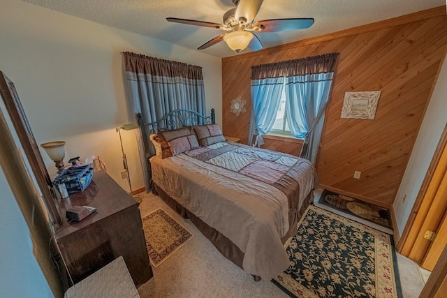 bedroom with wooden walls, a ceiling fan, a textured ceiling, and light colored carpet