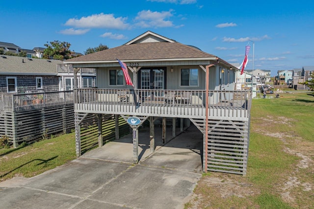 view of front facade with a porch, driveway, roof with shingles, a residential view, and a carport