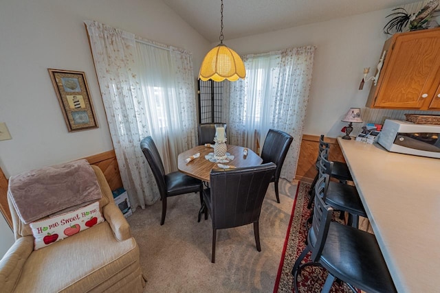 dining area featuring vaulted ceiling and light colored carpet