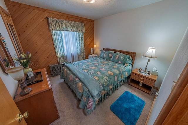 bedroom with carpet, wooden walls, and a textured ceiling