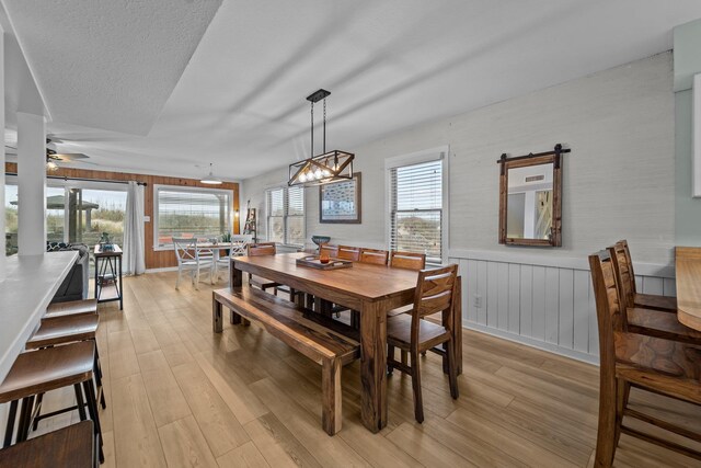 dining area with light wood-style flooring, ceiling fan, a textured ceiling, and wainscoting