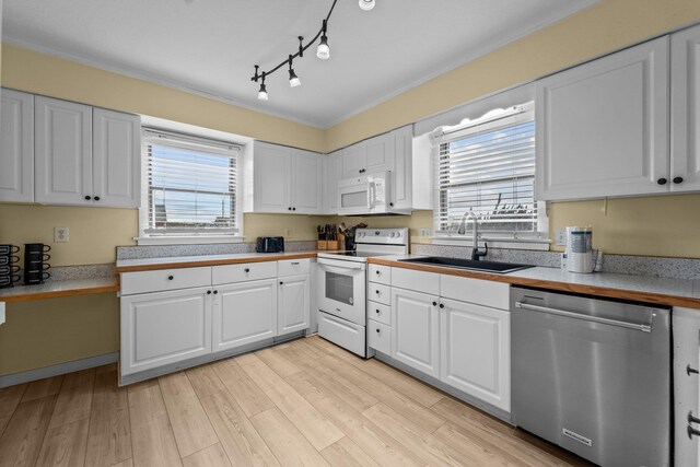 kitchen featuring white appliances, white cabinets, a sink, and light countertops