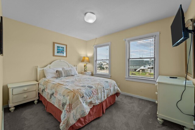 bedroom with dark colored carpet and baseboards