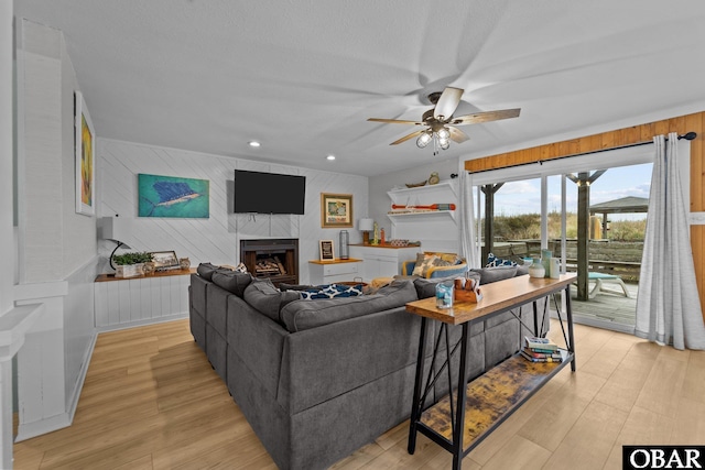 living room with light wood-style floors, a tile fireplace, ceiling fan, and recessed lighting