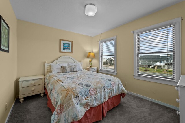 bedroom featuring dark colored carpet and baseboards