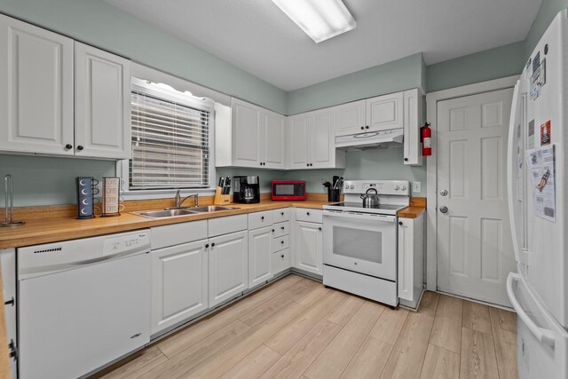 kitchen with white appliances, butcher block countertops, a sink, and under cabinet range hood