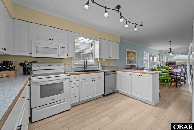 kitchen featuring white appliances, white cabinets, a peninsula, light countertops, and a sink