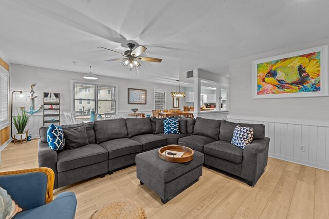 living room with ceiling fan, light wood-type flooring, wainscoting, and visible vents