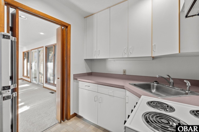 kitchen with light countertops, white cabinets, a sink, and white electric range oven