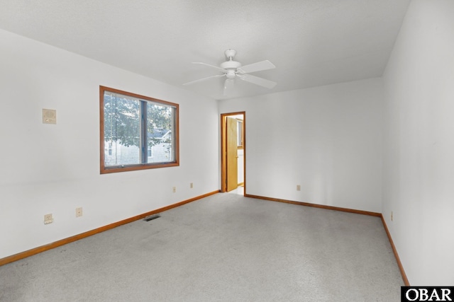 carpeted empty room with visible vents, ceiling fan, and baseboards