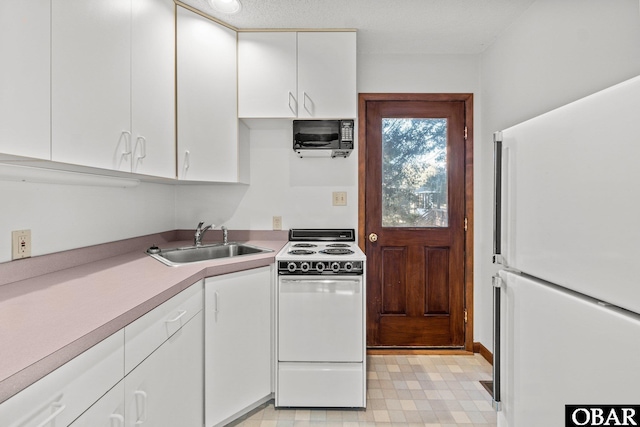 kitchen featuring light floors, light countertops, white cabinetry, a sink, and white appliances